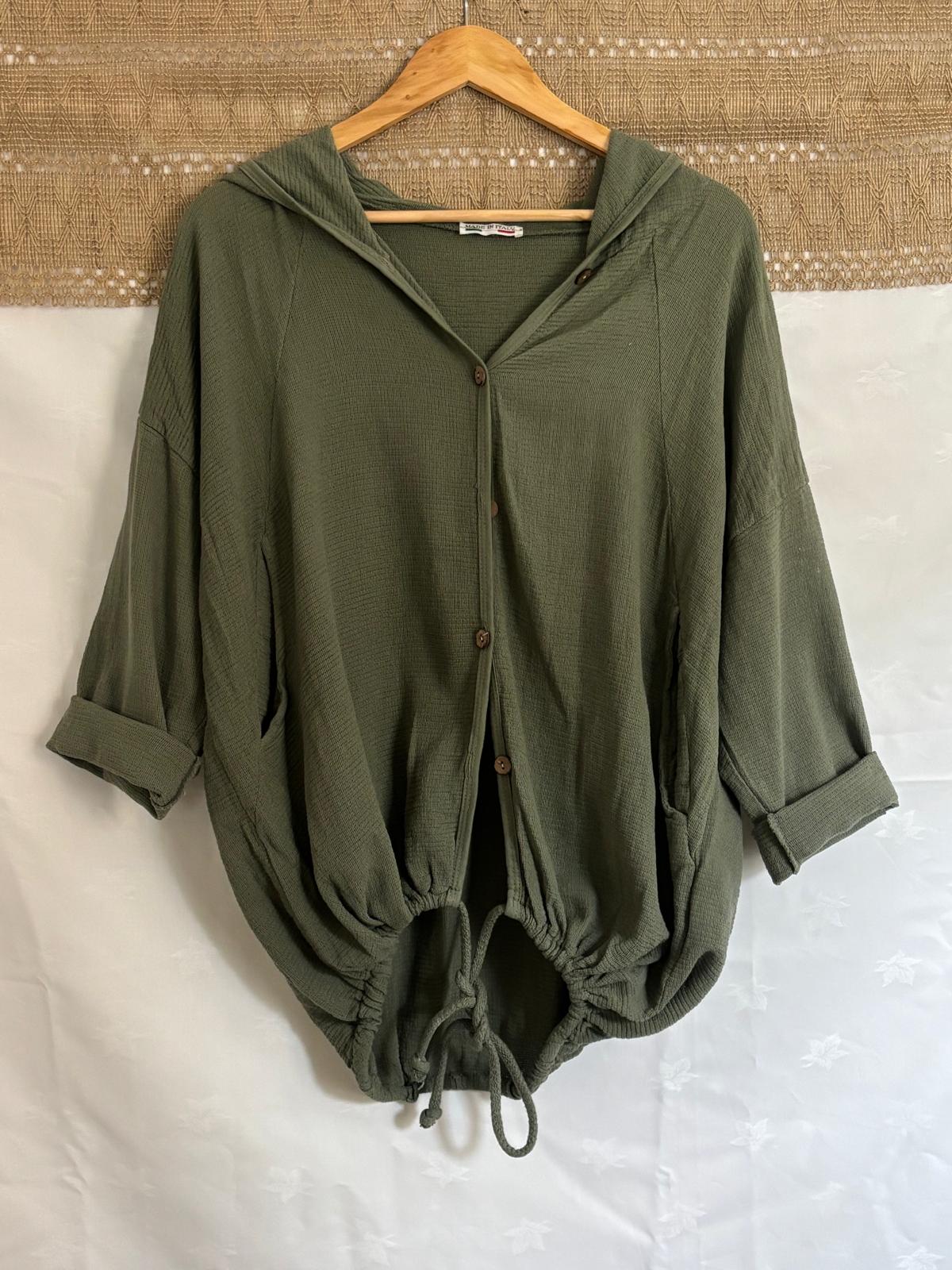 Green hooded outfit on a hanger against a textured wall and white surface.